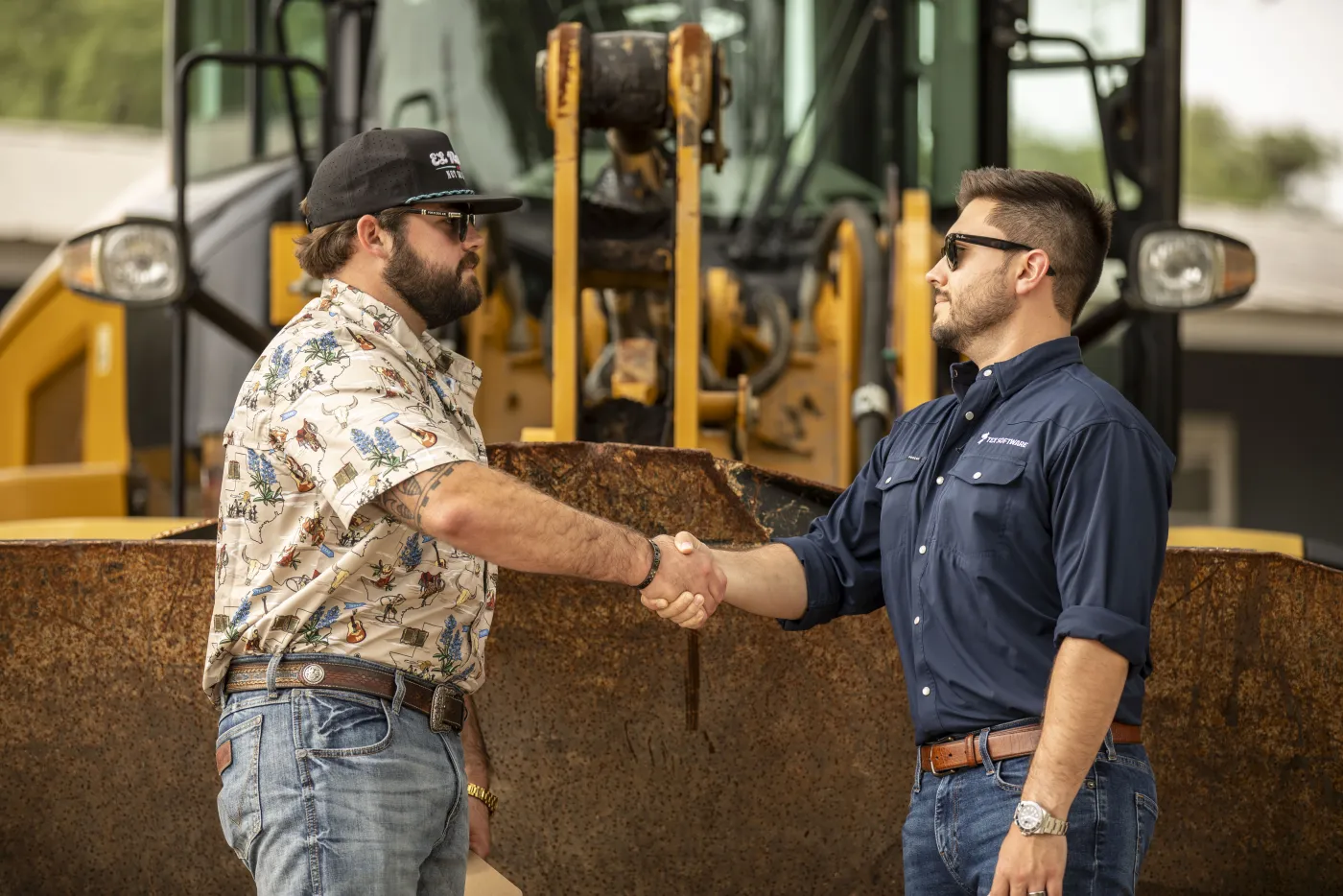 Handshake closing a deal in front of a raised loader bucket