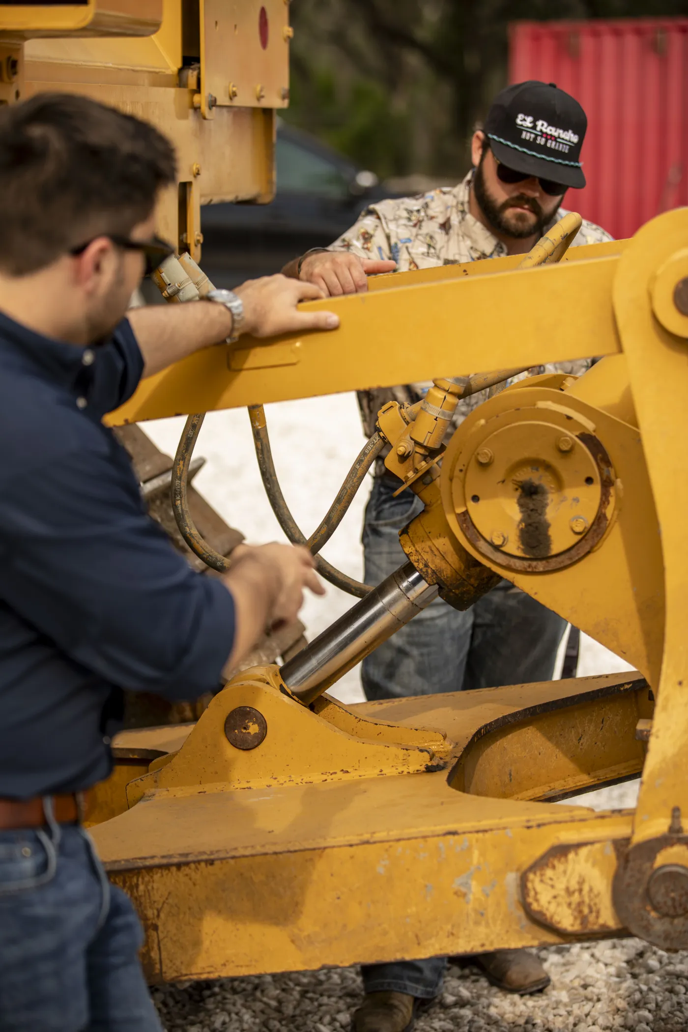 Two mechanics inspecting a hydraulic ram together at the yard
